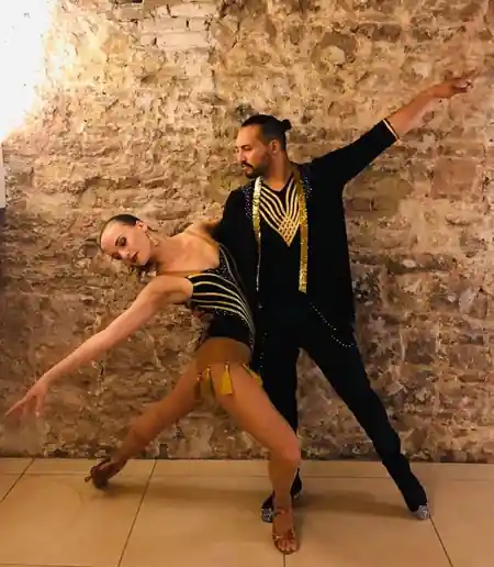 Latin dance couple in a stylized pose against a stone wall at Oropuro Amsterdam — salsa venue in Amsterdam