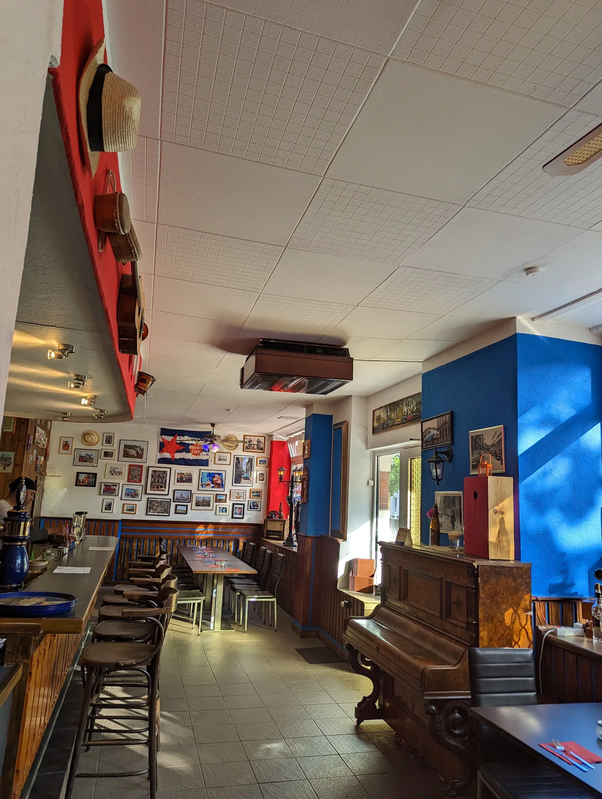 Interior of A lo Cubano in Braunschweig with bar, stools, upright piano and Cuban decor.