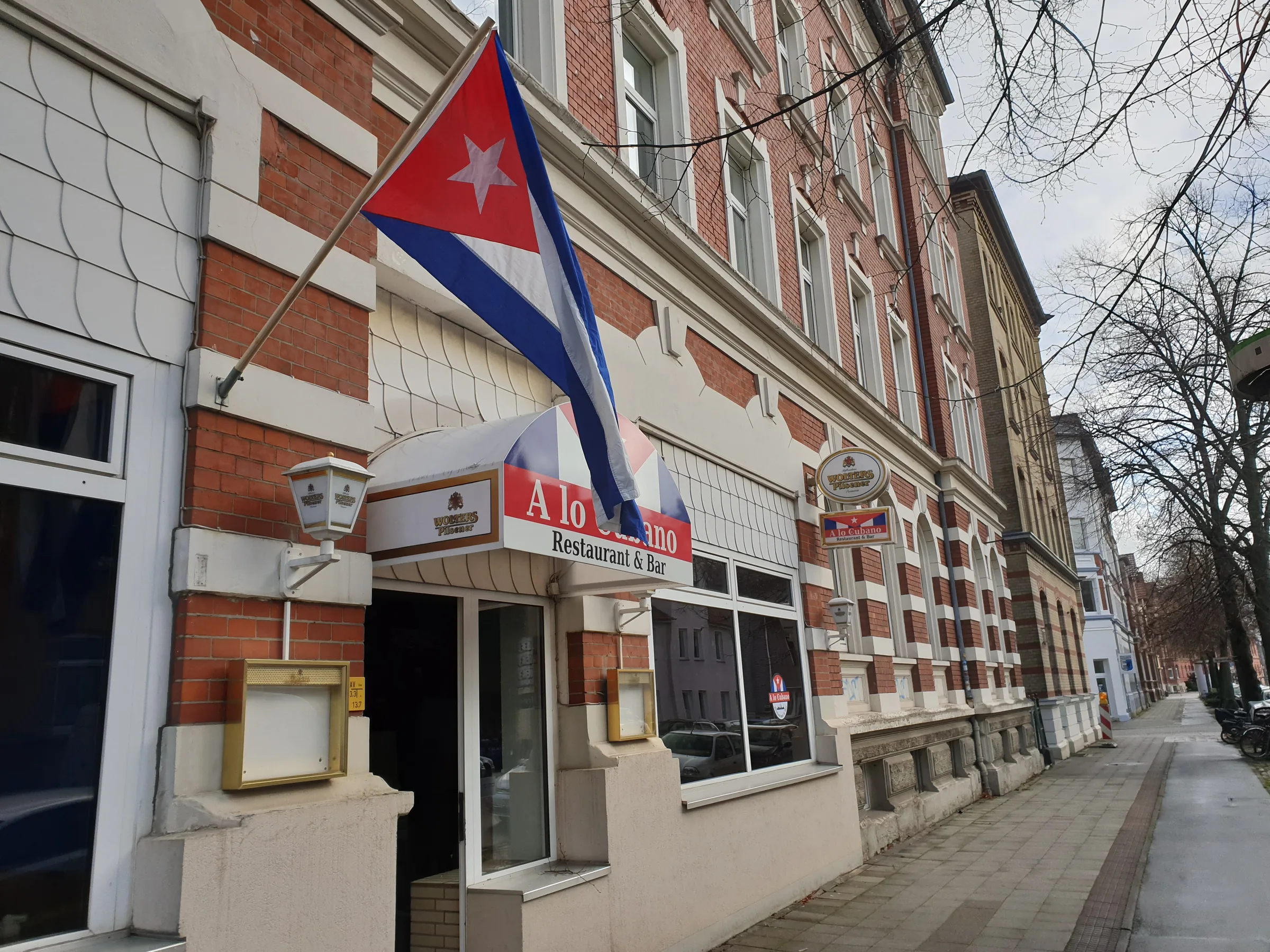 Street view of the A lo Cubano salsa bar entrance in Braunschweig with the Cuban flag out front.