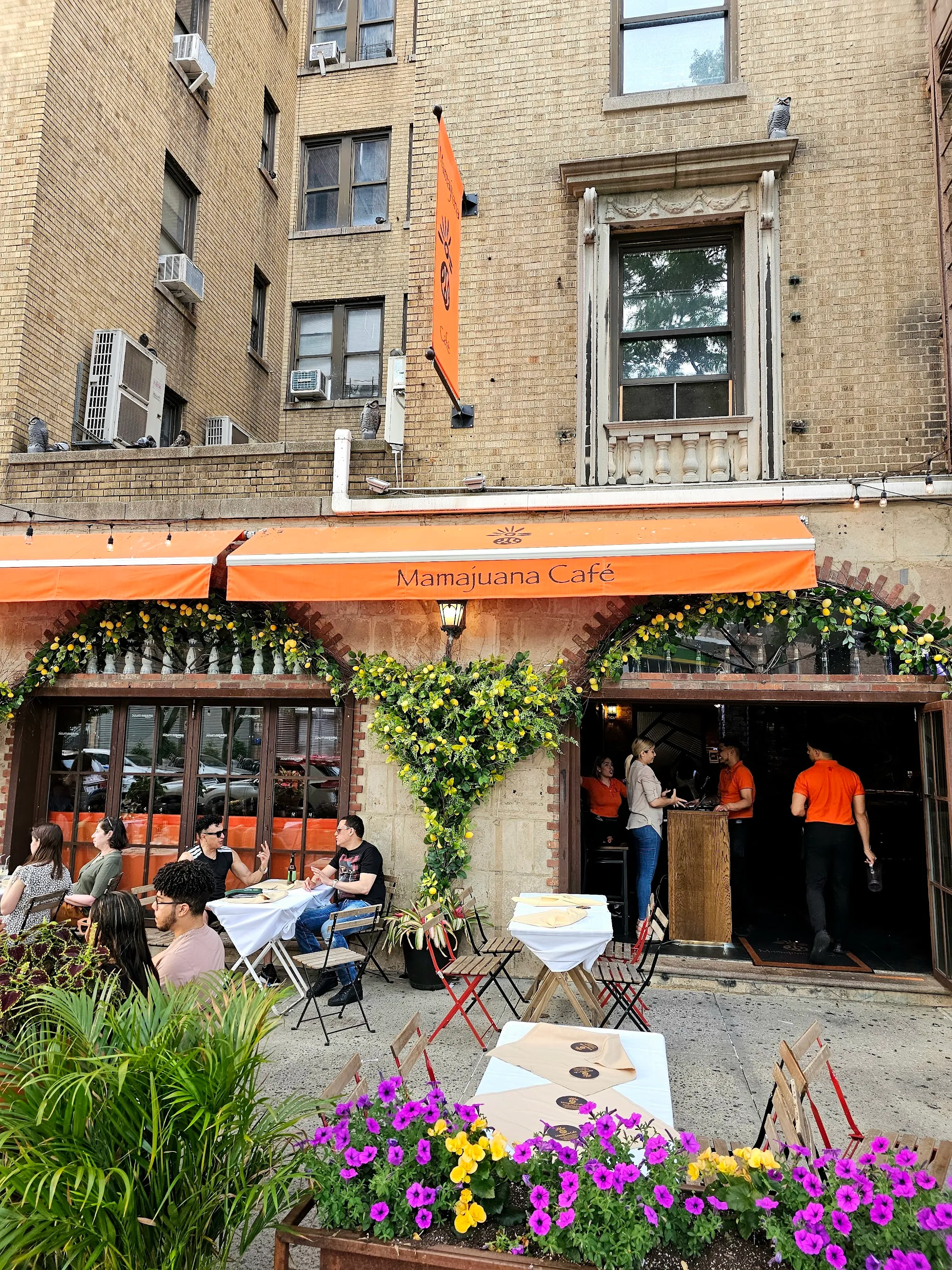 Mamajuana Cafe storefront and outdoor patio in New York with branded orange awning