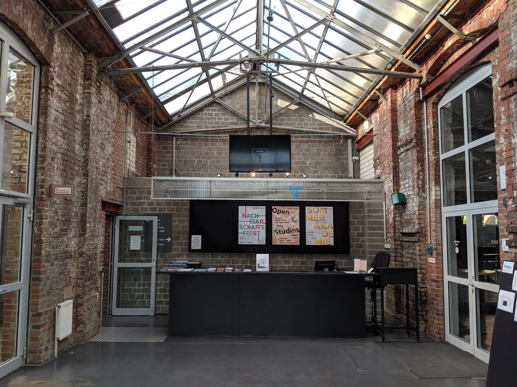 Brick and glass foyer entrance of Tanzhaus NRW with event posters in Düsseldorf