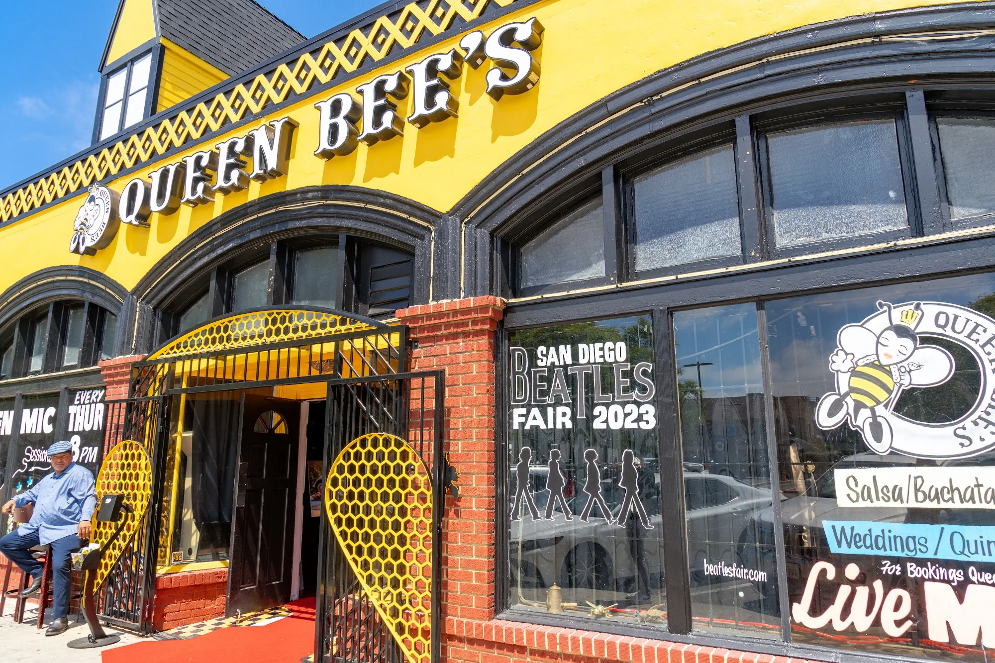 Queen Bee's entrance and yellow signage in San Diego, listing salsa, bachata and live music