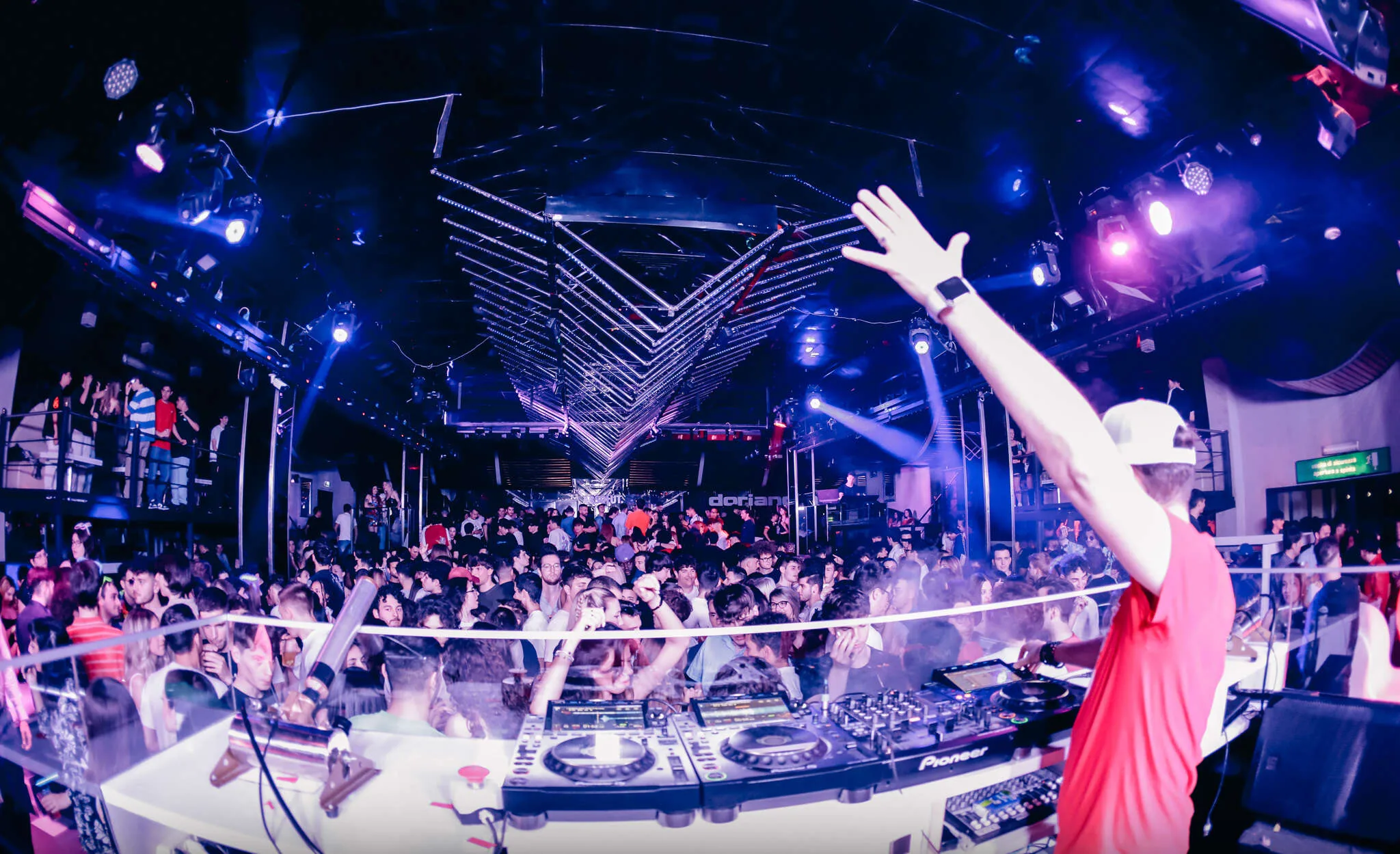 DJ raising hands at crowd under V-truss lighting at Discoteca Dorian Gray Verona