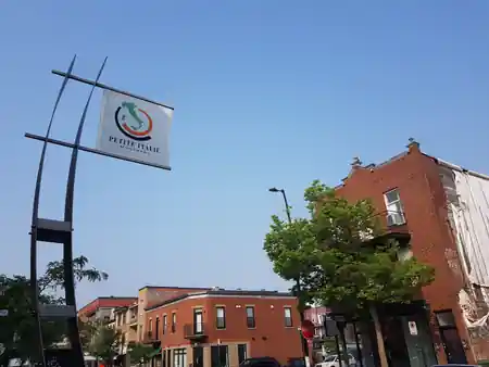 Park of Little Italy Montreal — Petite Italie neighbourhood sign with brick buildings in background — salsa, bachata venue in Montreal