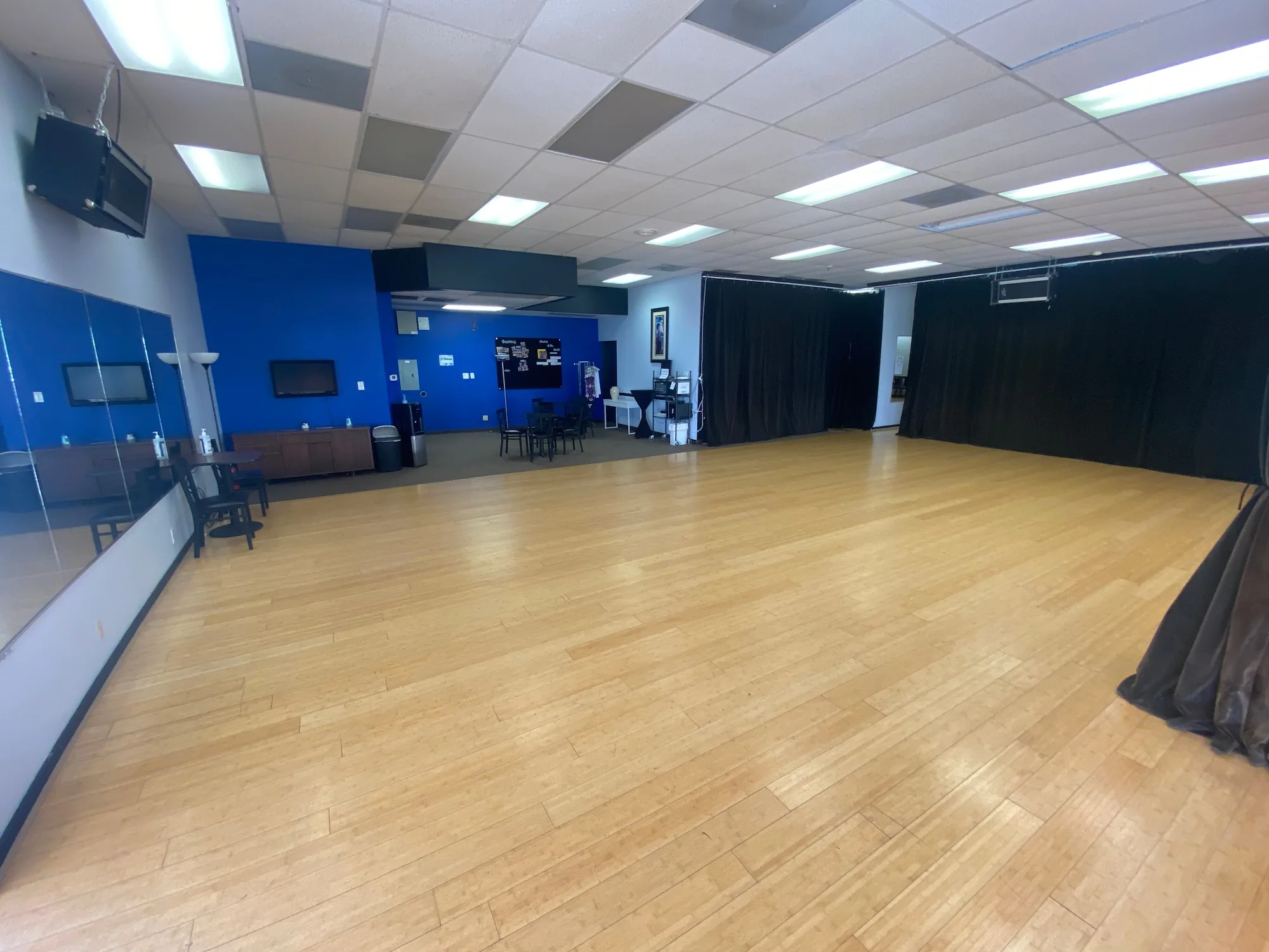 Spacious wooden dance floor with mirrors and blue accent wall at Austin Uptown Dance, Austin