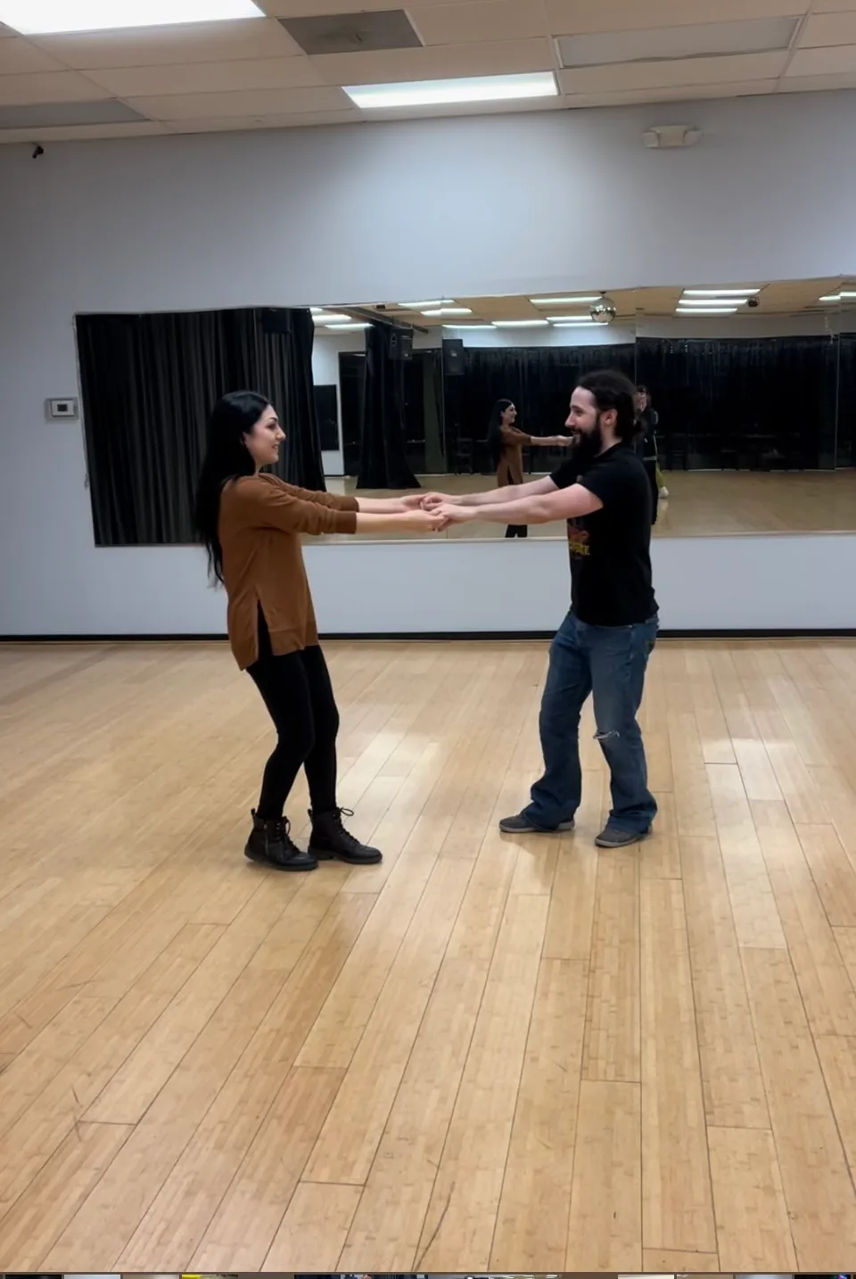 Couple practicing a partner-dance move in the mirrored studio at Austin Uptown Dance, Austin