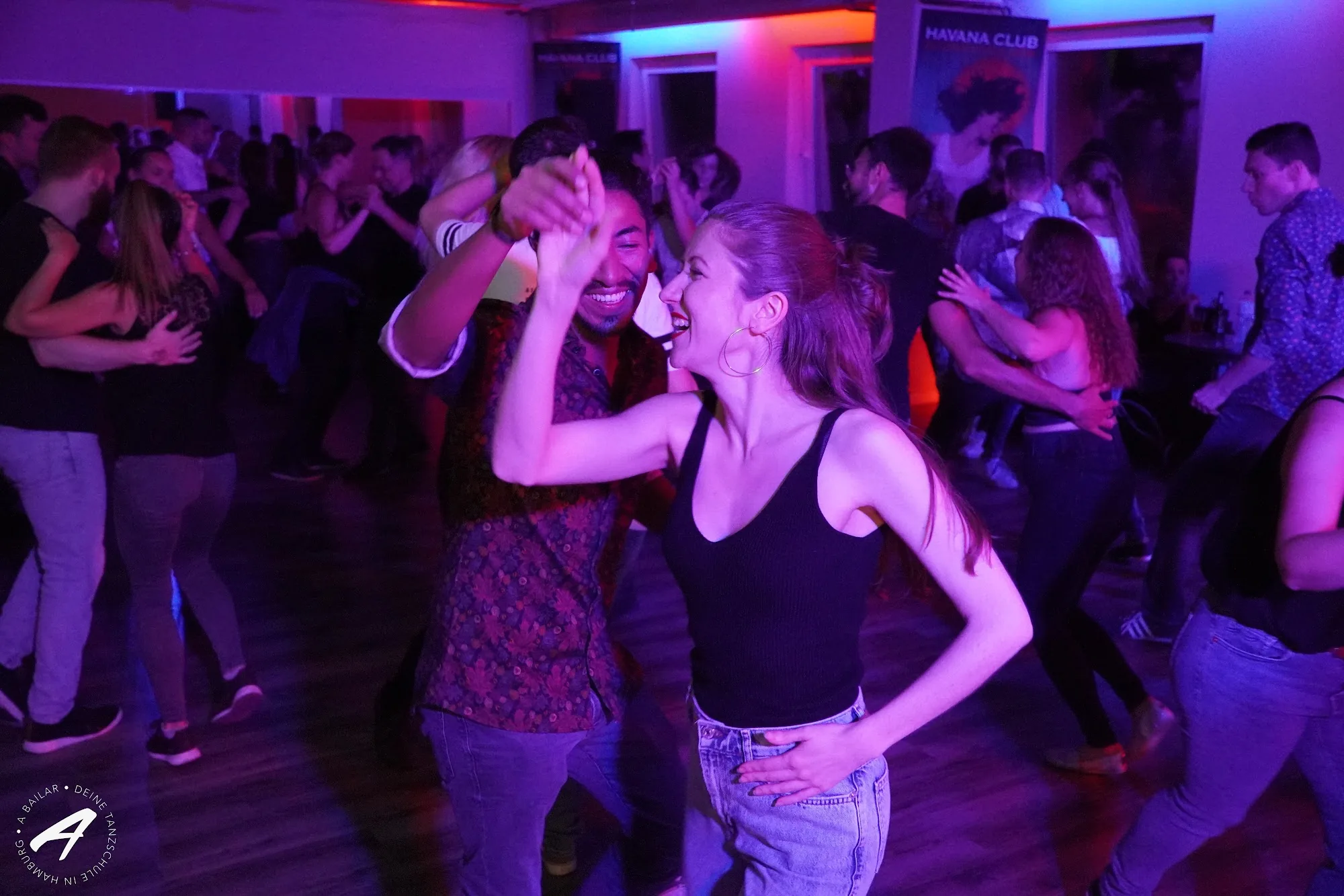 Salsa couple dancing on a packed dance floor at A Bailar Hamburg