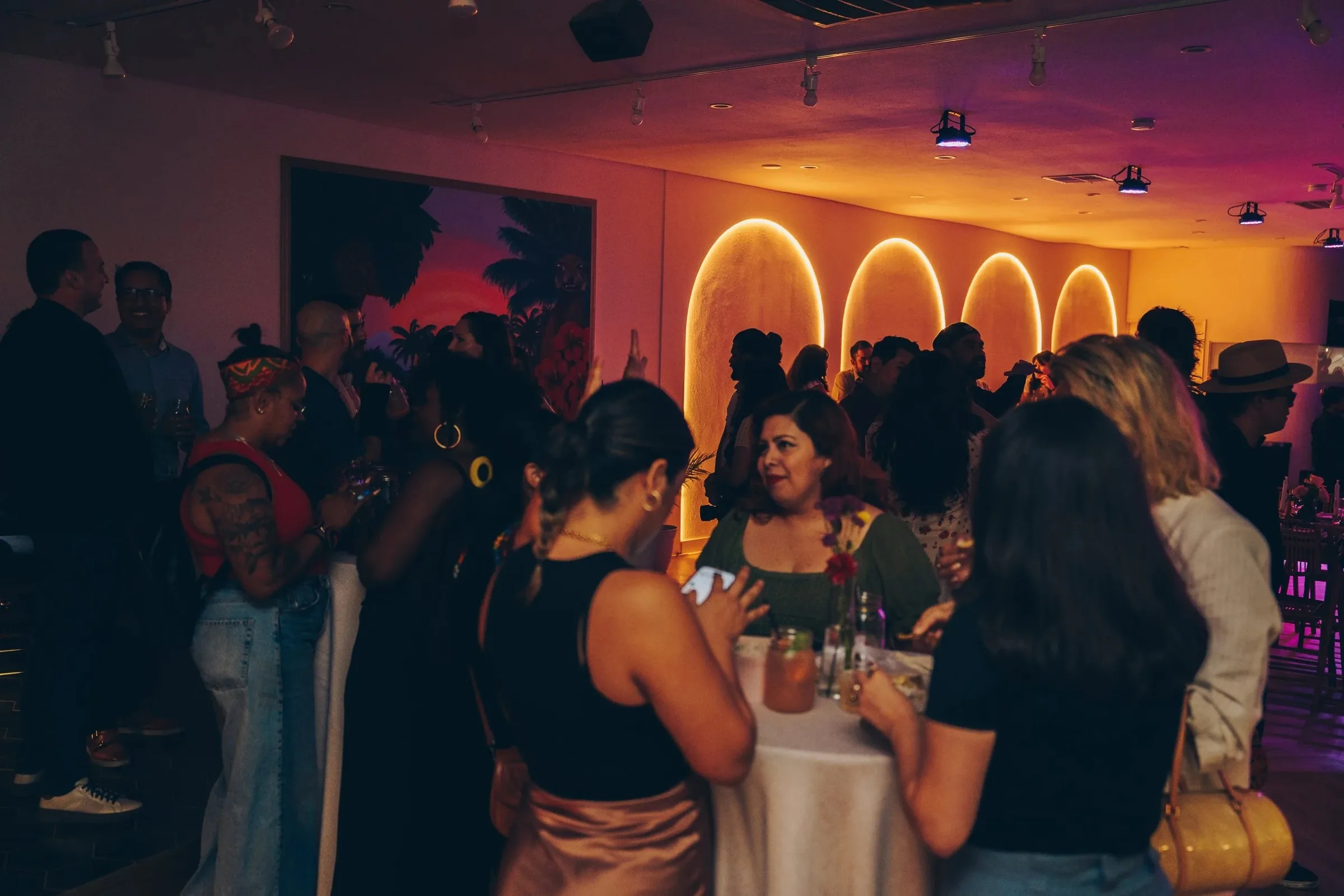 Guests socializing at a vibrant evening event inside Little Light Venue in Los Angeles with purple and pink ambient lighting