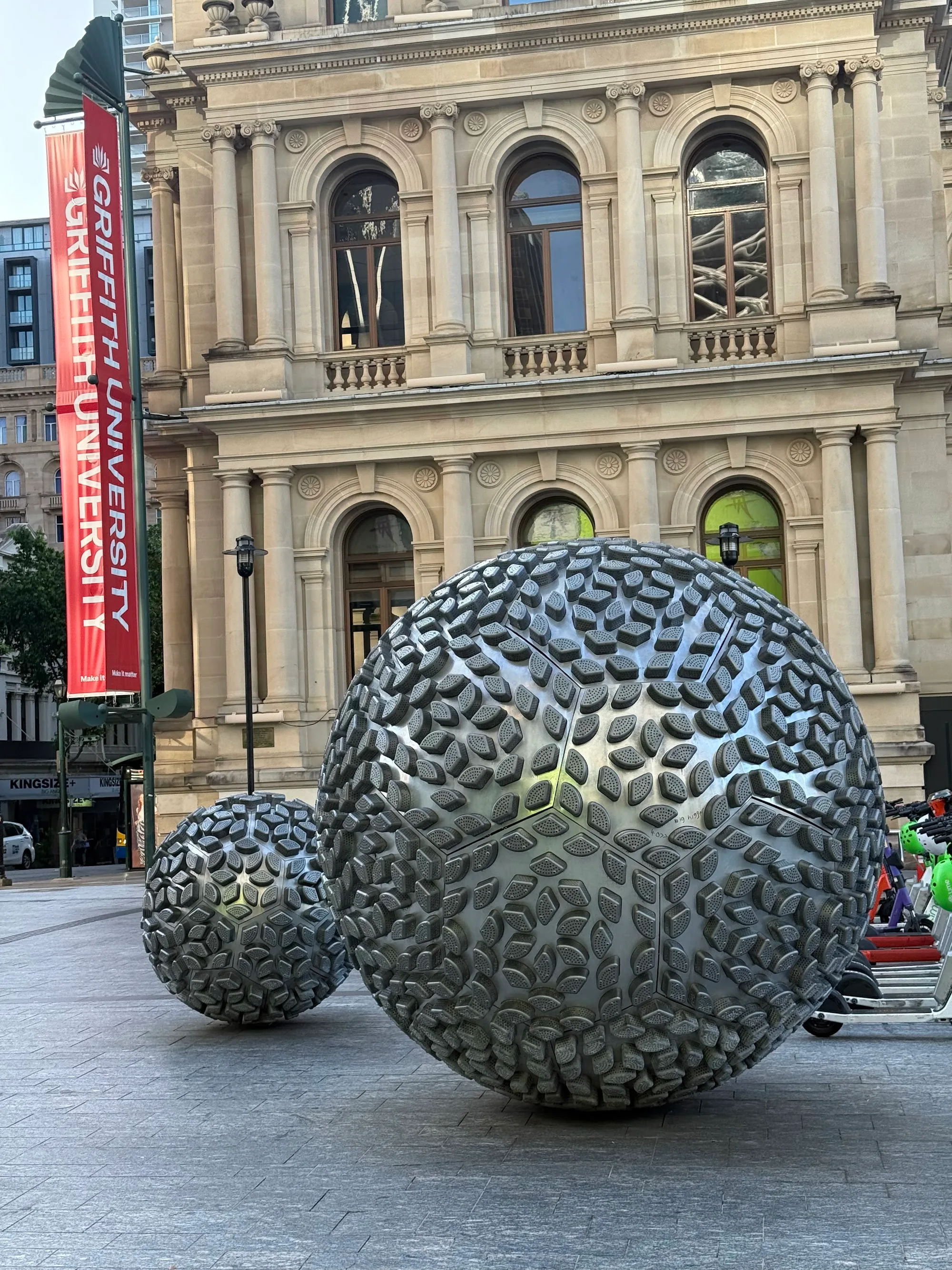 Reddacliff Place Brisbane — sphere sculptures with Treasury building facade and Griffith University sign
