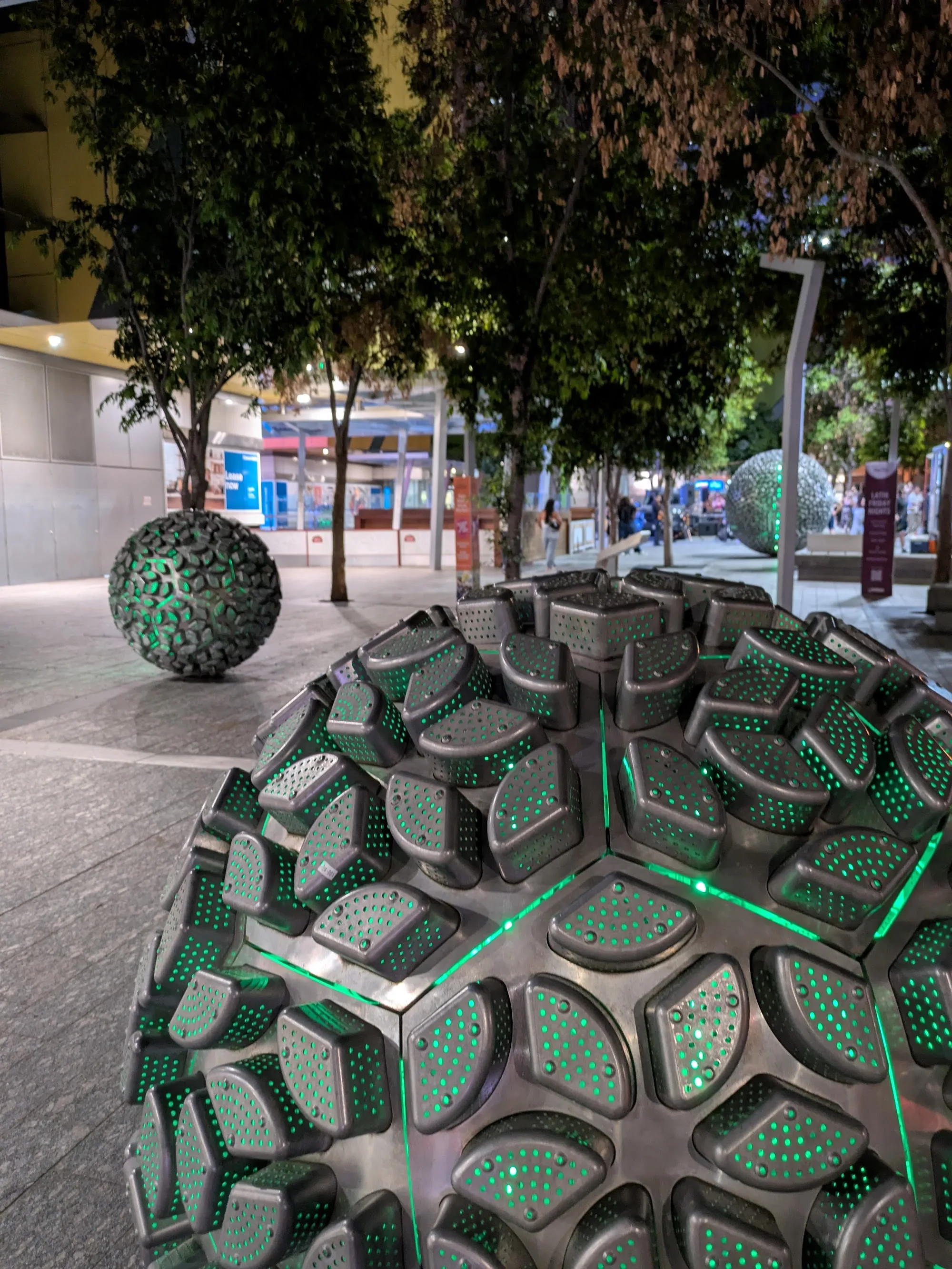 Reddacliff Place Brisbane at night — sphere sculptures lit with green LEDs and trees in background