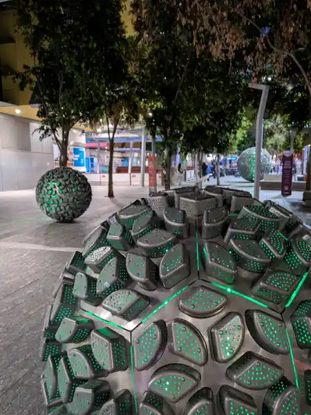 Reddacliff Place Brisbane at night — sphere sculptures lit with green LEDs and trees in background — salsa, bachata, merengue, reggaeton, mix venue in Brisbane