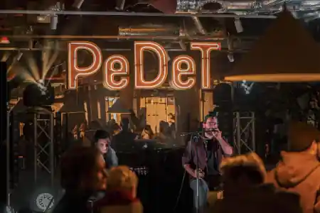 Live music performance on stage under the PeDeT neon sign at Renoma Wroclaw — salsa venue in Wroclaw