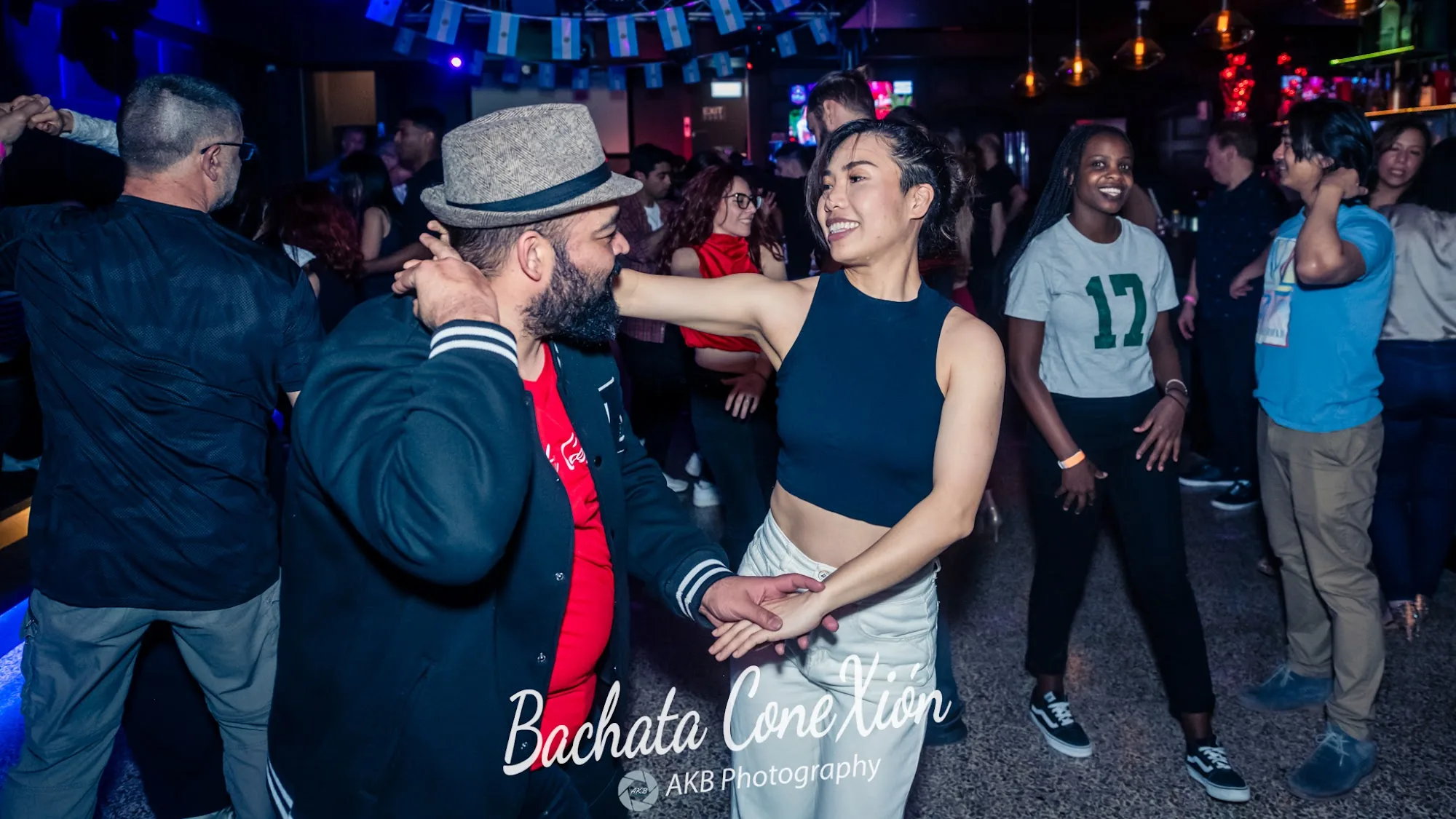 Couple dancing bachata on the crowded social floor at Bachata ConeXion in Melbourne