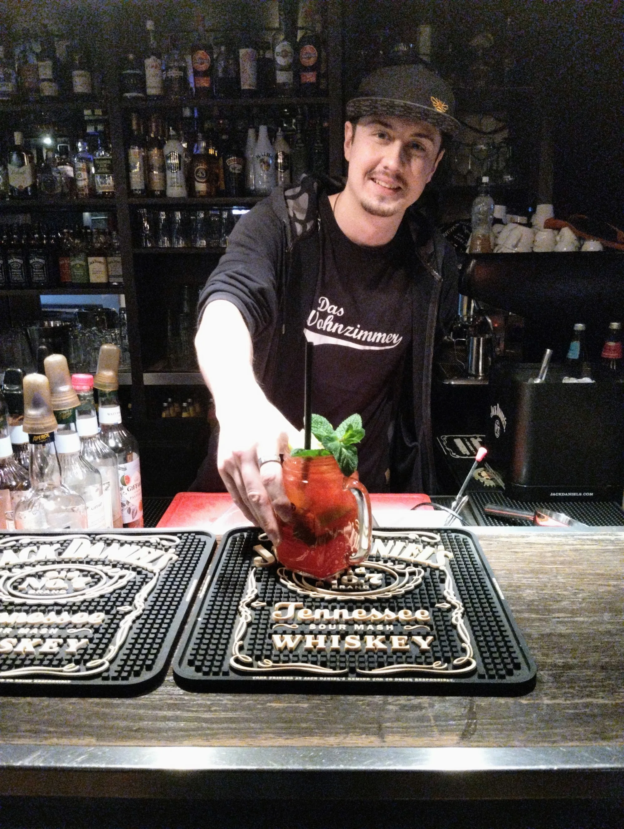 Bartender in branded shirt mixing a cocktail at the bar of Das Wohnzimmer in Wiesbaden
