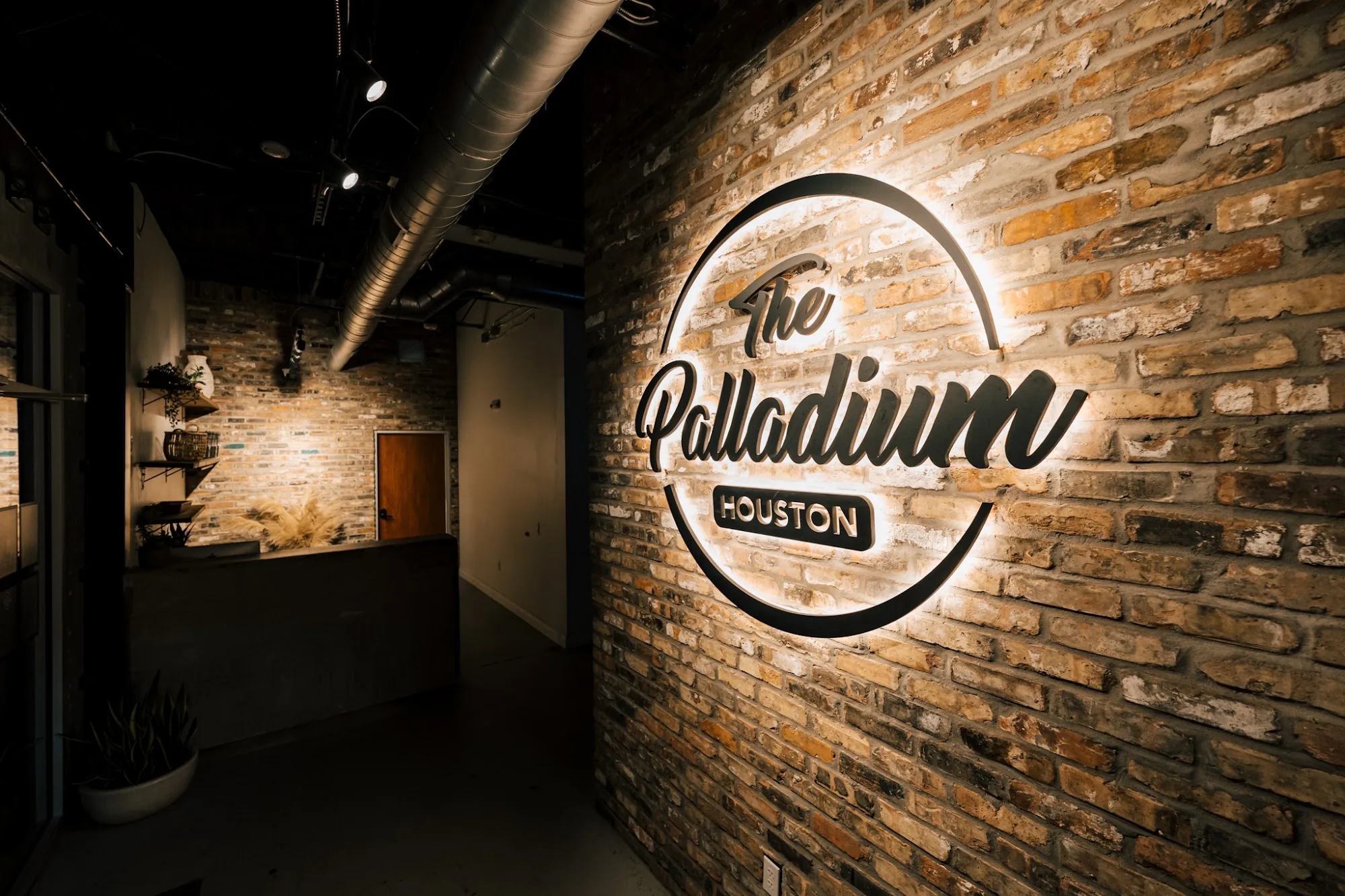 Lit The Palladium Houston logo on exposed brick at the venue entrance