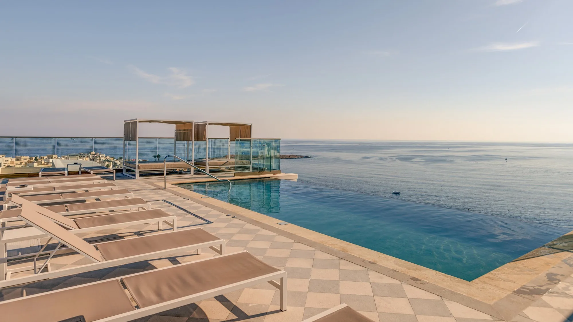 Infinity pool with sea view and sun loungers at AX Hotels Malta, Sliema
