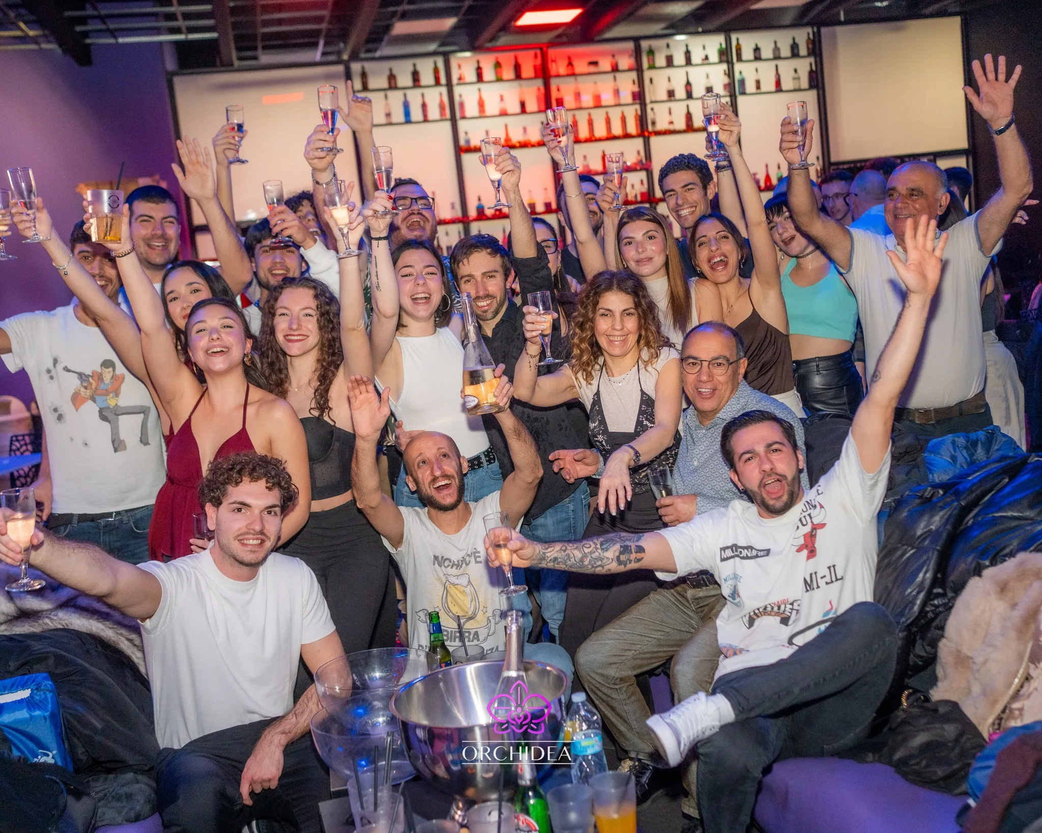 Crowd celebrating with raised glasses at Orchidea Club Latin night in Milan