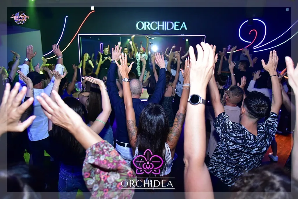 Packed dance floor with arms raised under stage lights at Orchidea Club Milan
