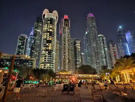 Evening crowd on the beach at Barasti Beach with Dubai Marina lit up behind — salsa, bachata venue in Dubai