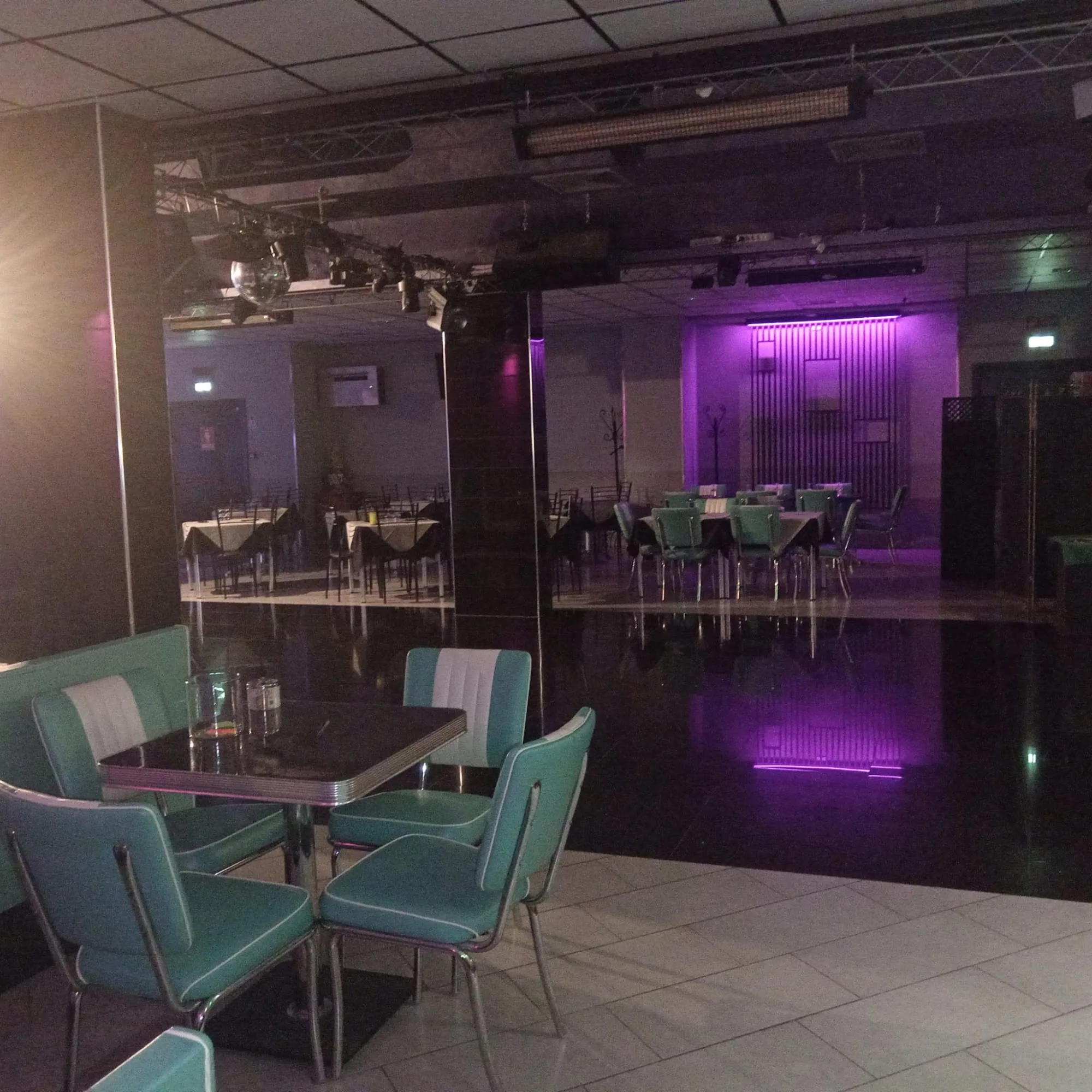 PERUNQUE interior — dance hall with mirror walls, seating booths and reflective dance floor under purple lighting