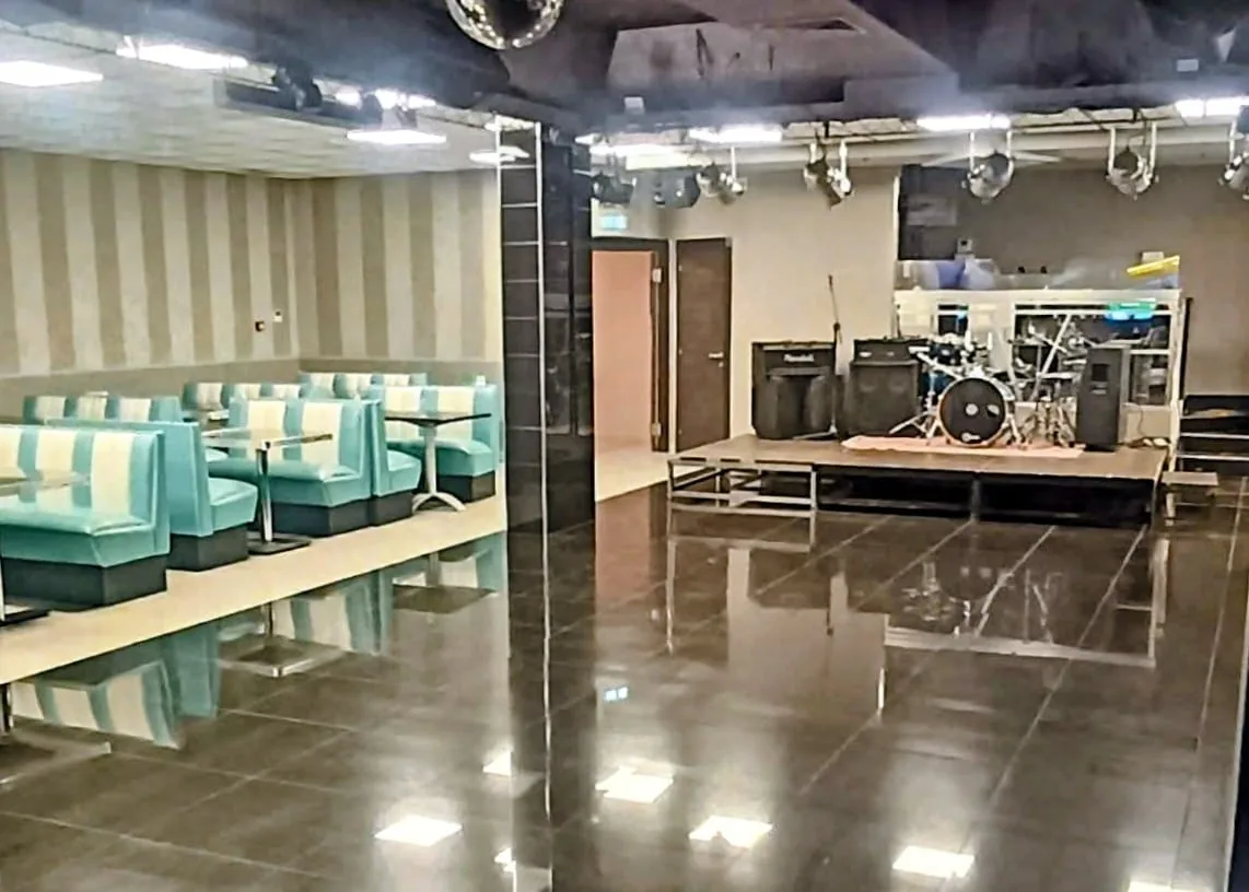 PERUNQUE dance hall — live band stage with drum kit and seating booths, full venue view