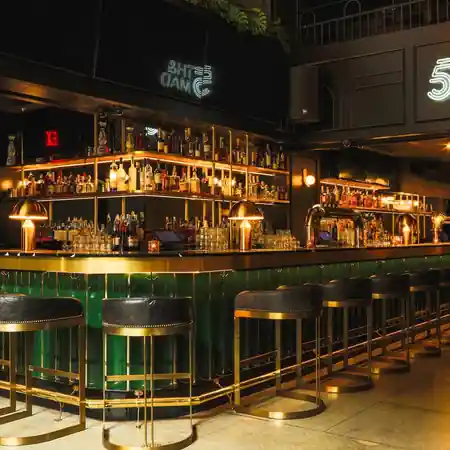 Green and gold cocktail bar with neon 5th & Mad branding, New York — salsa venue in New York