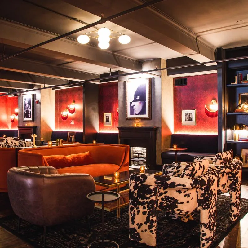 Moody lounge area with velvet sofas and art at 5th & Mad in New York