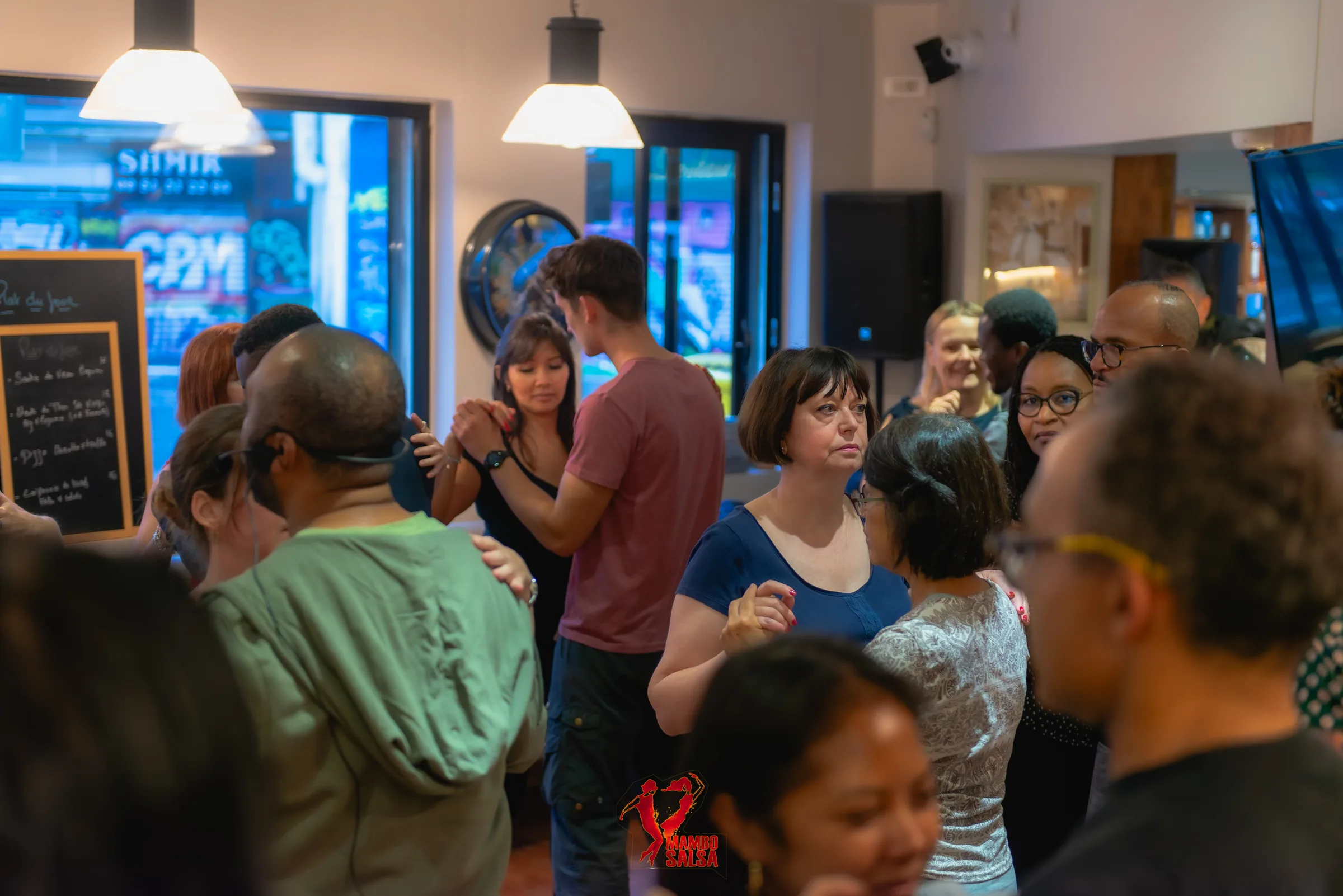 Crowd mingling indoors with club lighting at a Mambo Salsa party at The Station, Paris