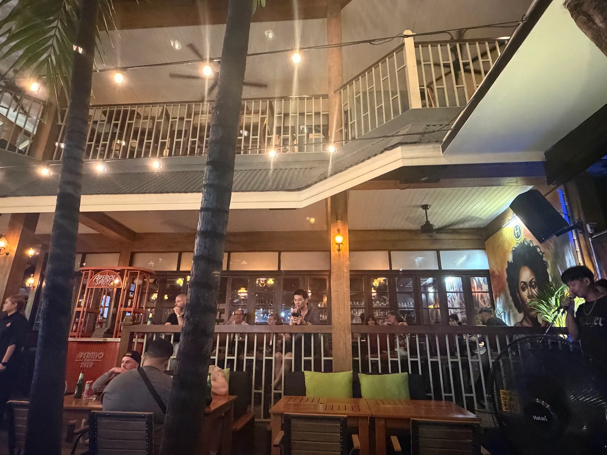Multi-level bar interior with palm trees and crowd at Hemingways Bangkok
