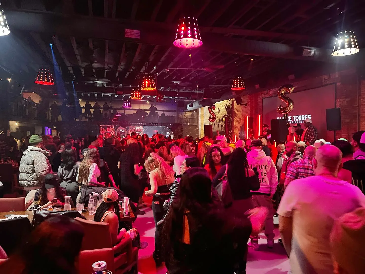 Packed party crowd under red lampshades at Atolye Venue & Bar in New York