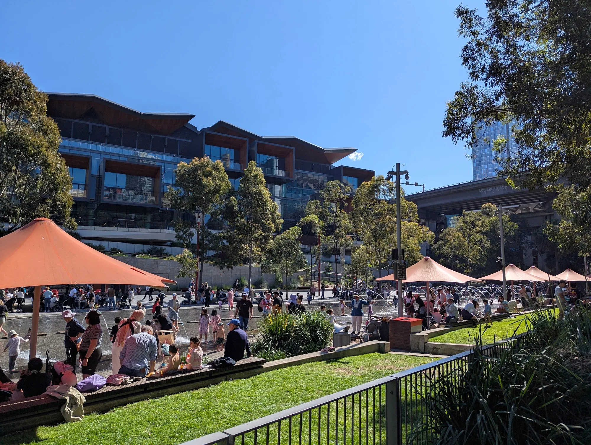 Crowd enjoying Palm Grove at Darling Harbour Sydney with orange sails and ICC backdrop, the Latin Nights setting