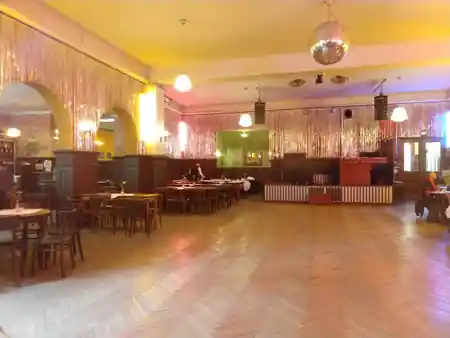 Historic ballroom with parquet dance floor, disco ball and gold tinsel curtains at Clärchens Ballhaus, Berlin — salsa venue in Berlin