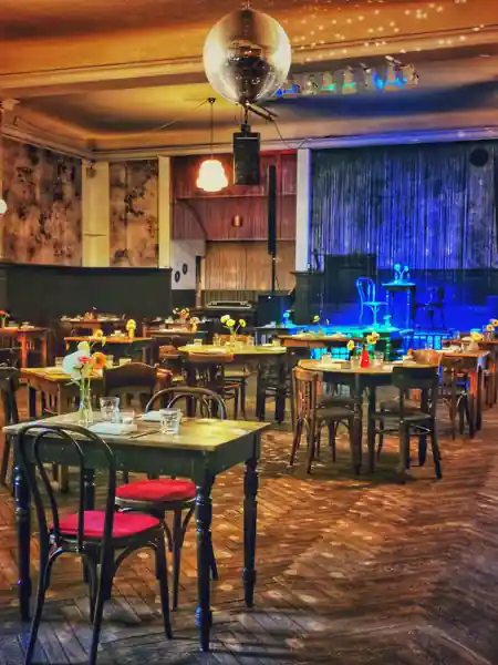 Ballroom interior with disco ball, stage and bistro tables at Clärchens Ballhaus, Berlin — salsa venue in Berlin