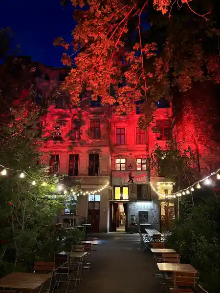Red-lit night facade of Clärchens Ballhaus with illuminated signage and beer-garden tables, Berlin — salsa venue in Berlin