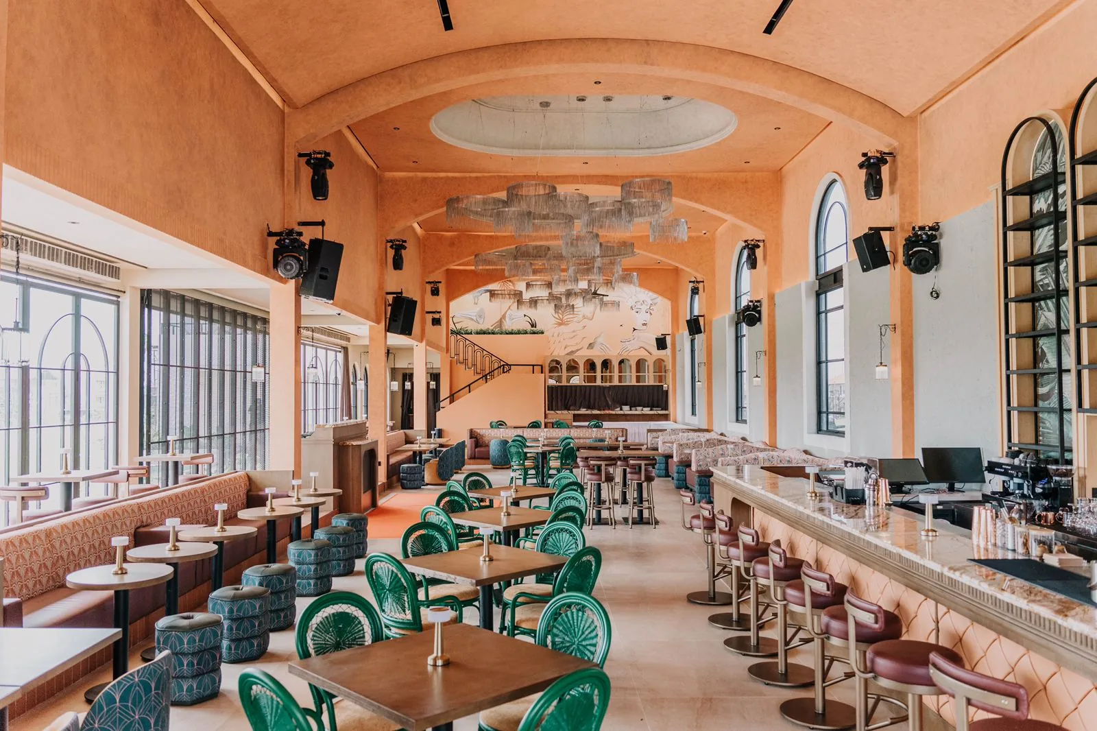 Coral-walled dining hall with chandeliers and bar at Amavi venue in Canggu, Bali
