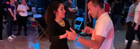 Couple dancing on the wooden floor at an Austin Inspired Movement social in Austin — salsa, bachata, zouk venue in Austin