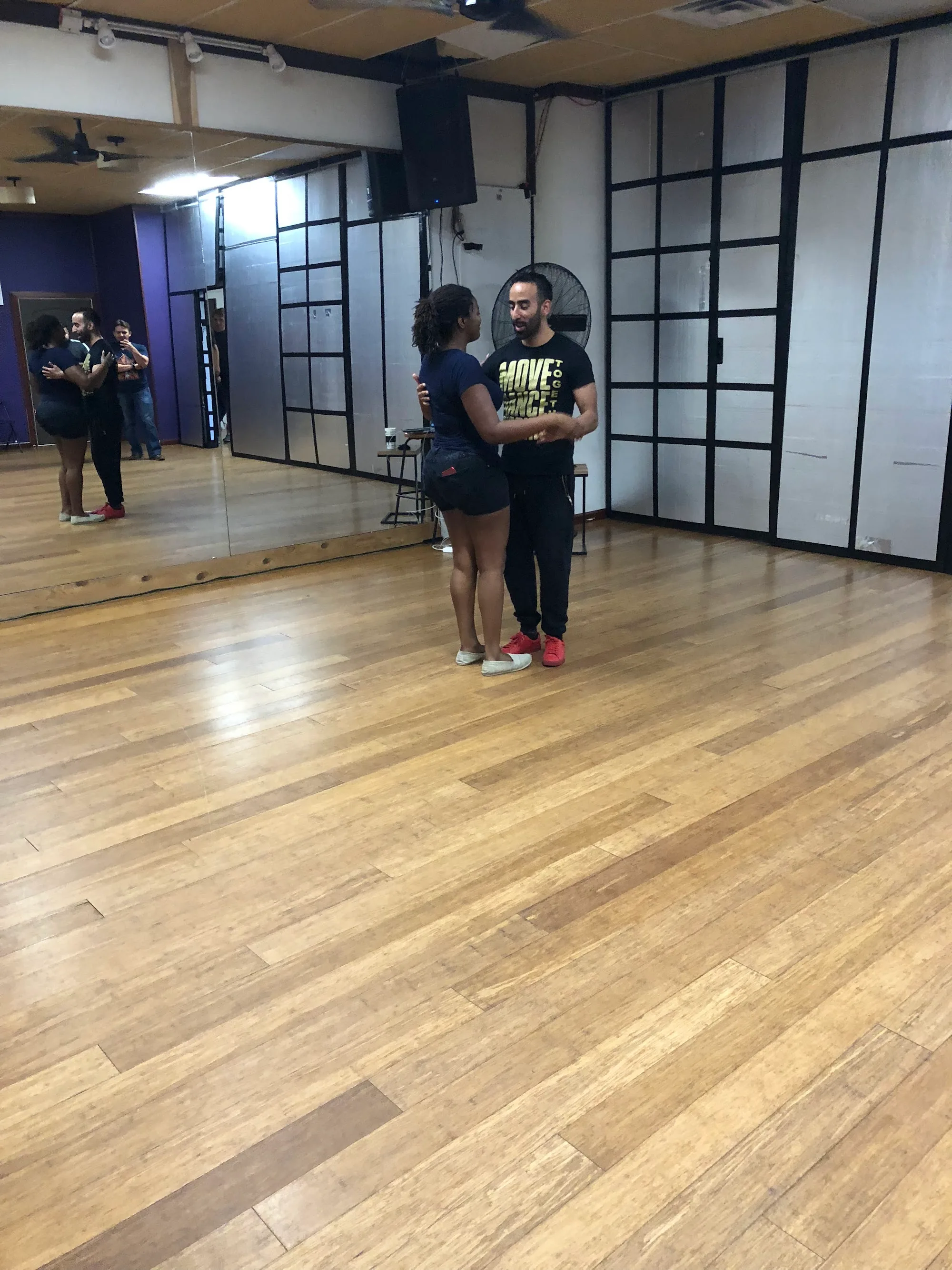 Couple practicing partner dance on the wooden studio floor at Austin Inspired Movement