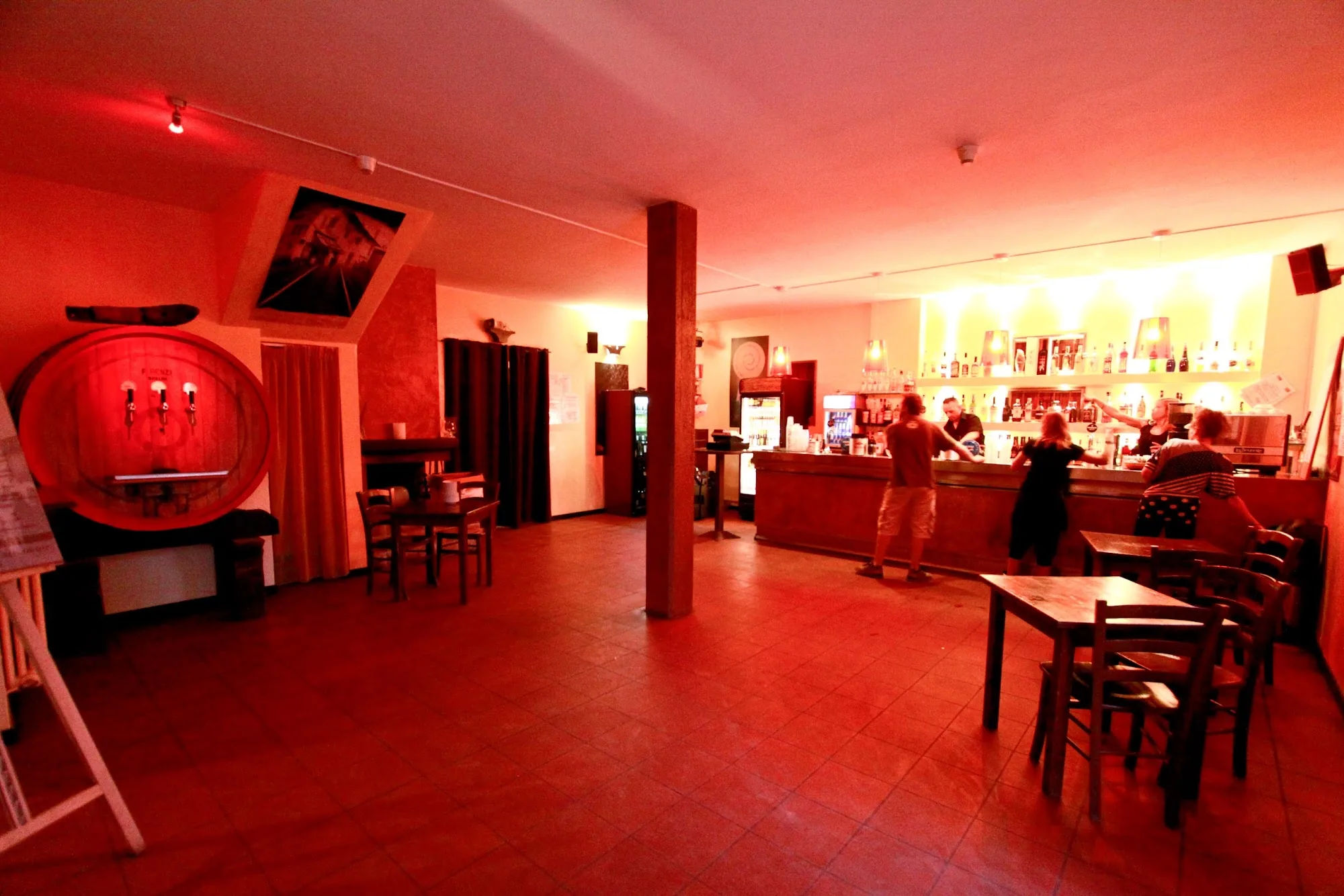 Red-lit bar and dance floor at Ca de Mandorli restaurant with people dancing