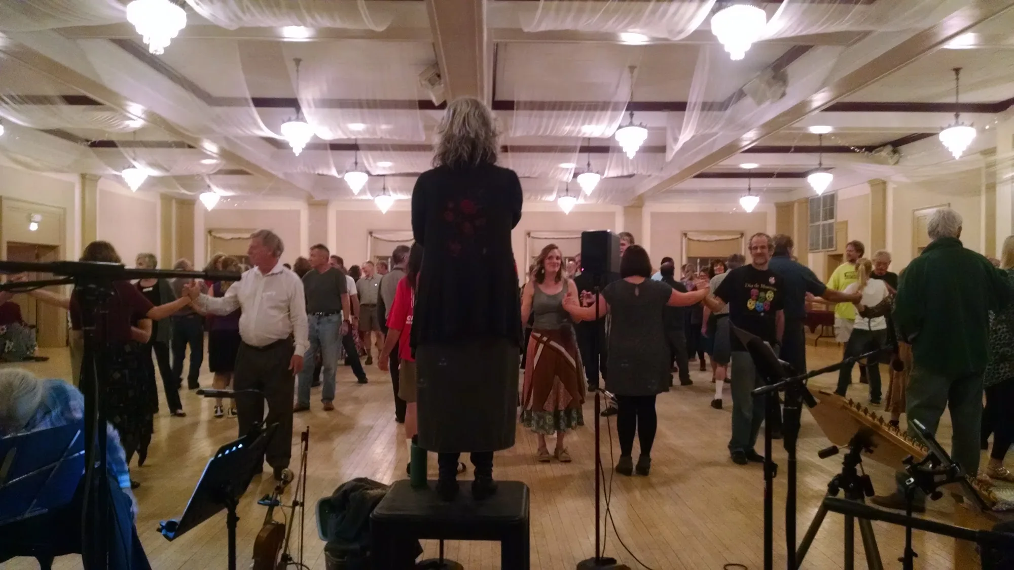 Social dancers holding hands on the wooden floor with live band at Highlands Event Center, Denver