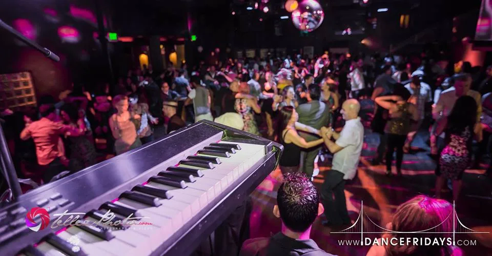 Packed salsa dance floor with club lighting and disco ball at Dance Fridays, San Francisco