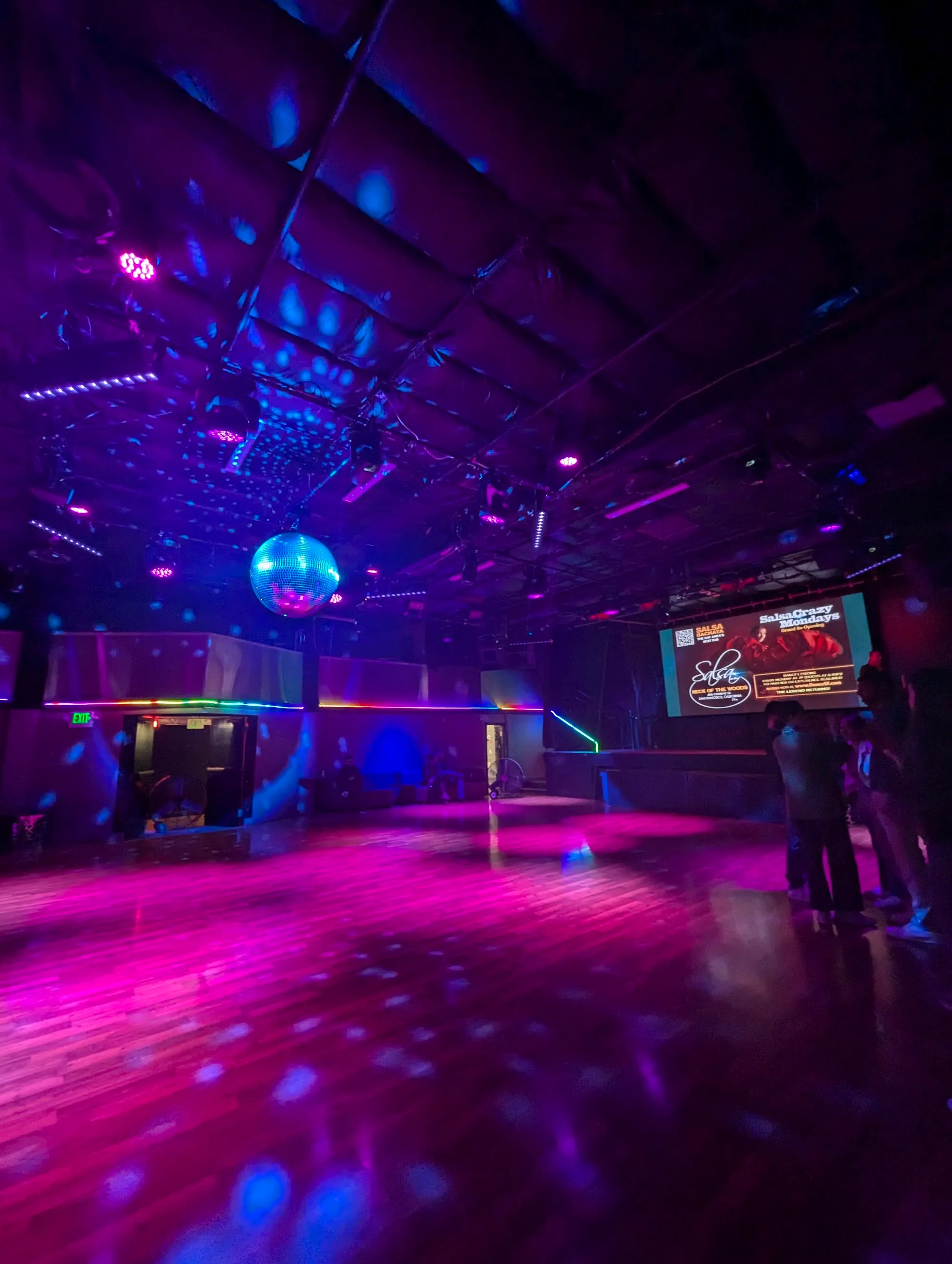 Empty wooden dance floor under purple lights and disco ball at Dance Fridays, San Francisco