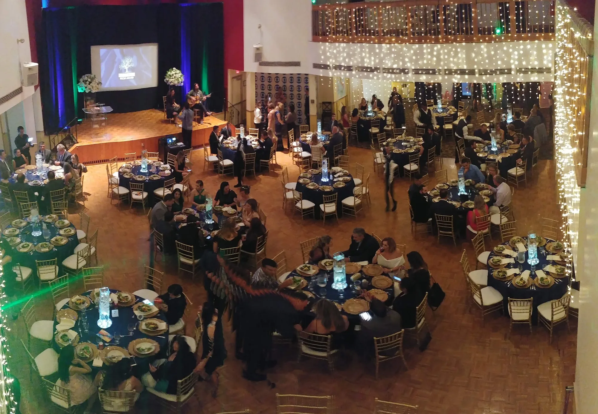 Crowd at a fairy-lit gala with a stage performance in the hall at Dante Alighieri Society, Cambridge