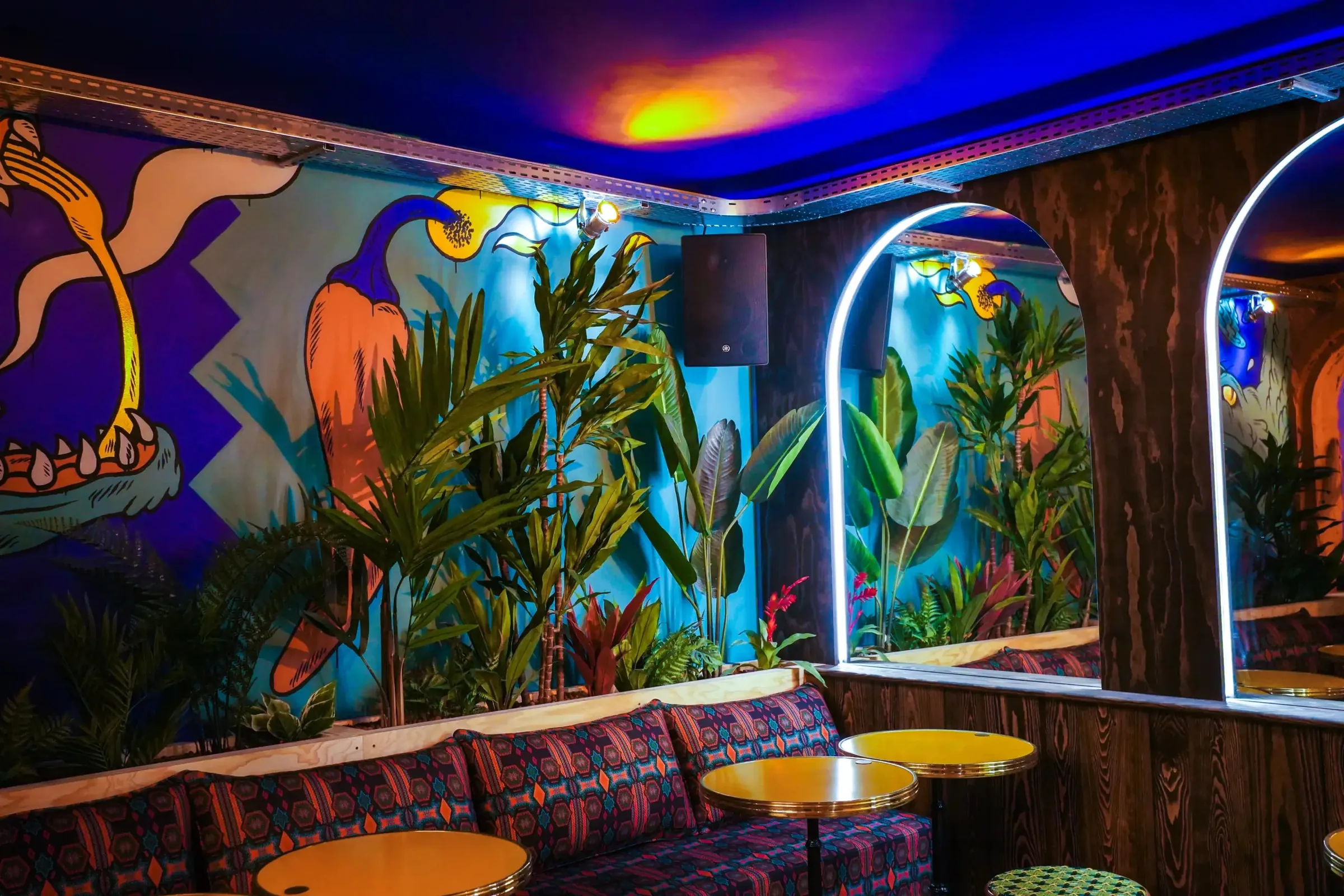 Interior lounge with tropical wall murals, banquette seating and round tables at Au Toucan Fringant, Bordeaux