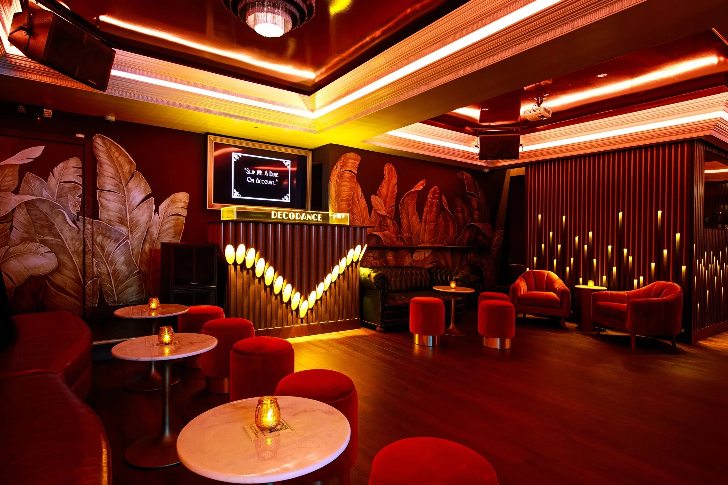 DecoDance Bar lounge and dance floor area in San Francisco with art deco tropical murals, red velvet seating, and open hardwood floor for Latin social dancing — salsa, bachata venue in San Francisco