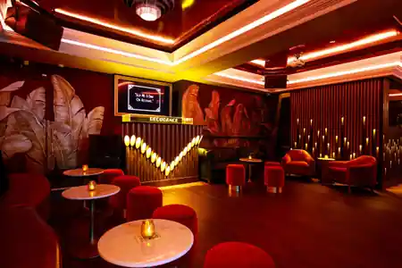 DecoDance Bar lounge and dance floor area in San Francisco with art deco tropical murals, red velvet seating, and open hardwood floor for Latin social dancing — salsa, bachata venue in San Francisco