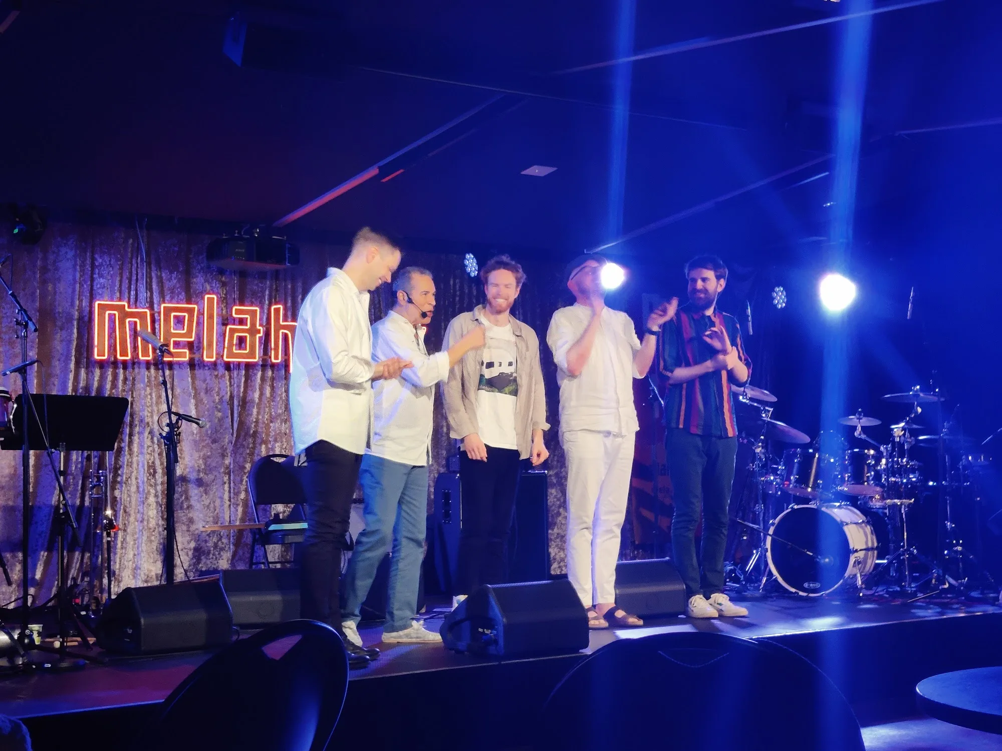 Performers on stage with Melahuset neon sign and drum kit at Melahuset in Oslo Norway