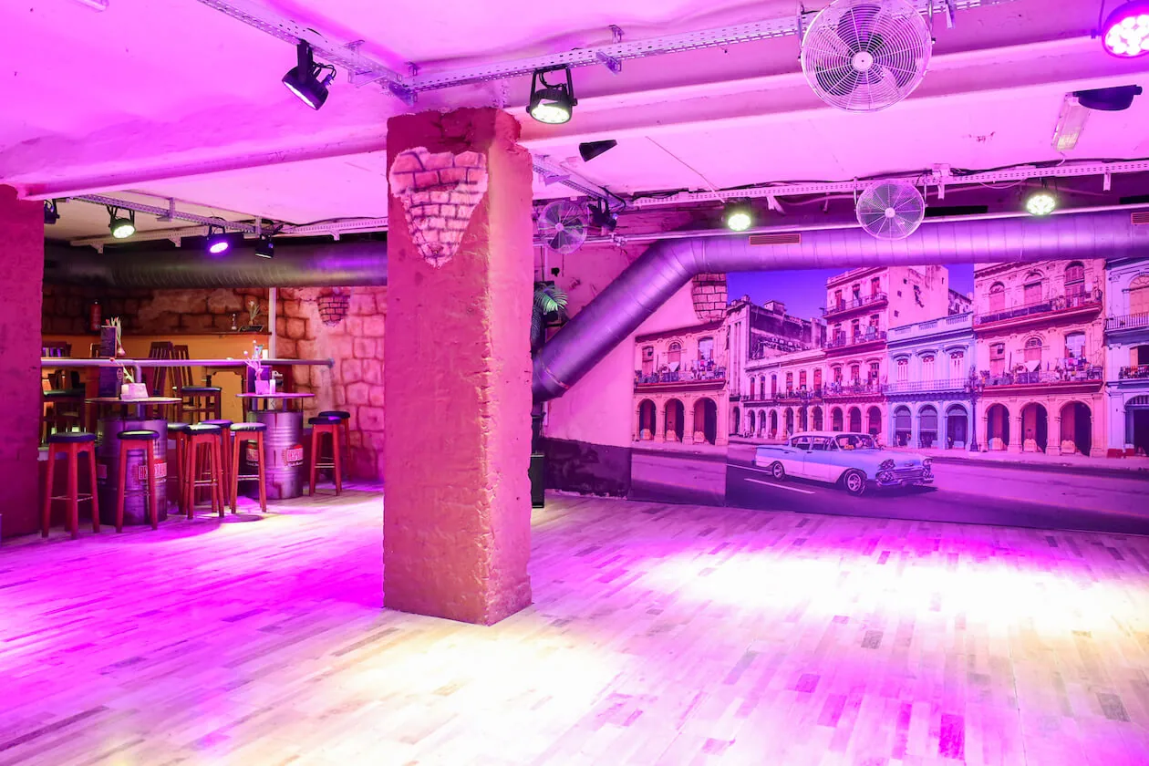 Wooden dance floor, bar and Havana street mural under purple club lighting at Havanna Star Karlsruhe