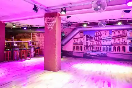 Wooden dance floor, bar and Havana street mural under purple club lighting at Havanna Star Karlsruhe, salsa, bachata venue in Karlsruhe