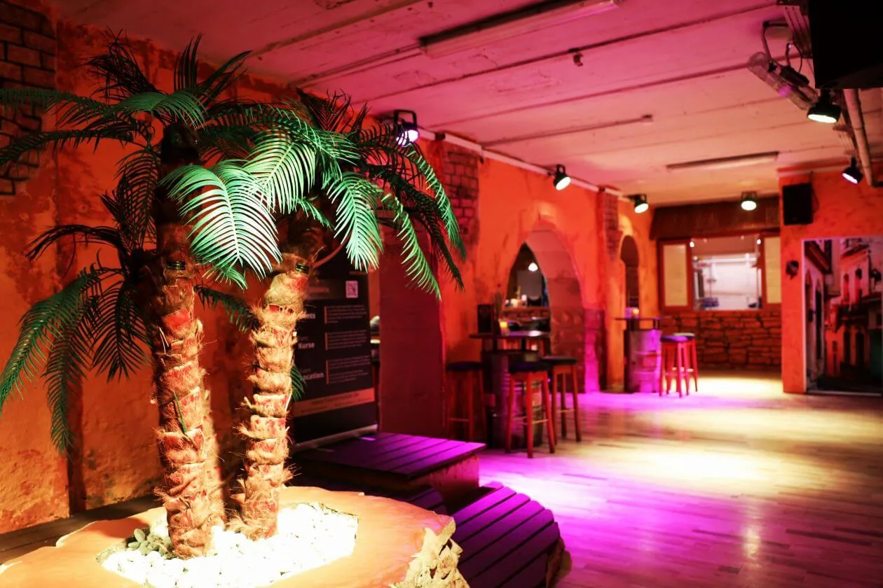 Lounge with palm-tree centerpiece and warm bar lighting inside Havanna Star Karlsruhe dance venue