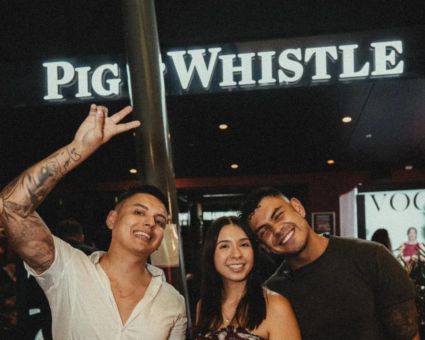 Group of friends posing under the Pig 'N' Whistle signage at night in Fortitude Valley, Brisbane